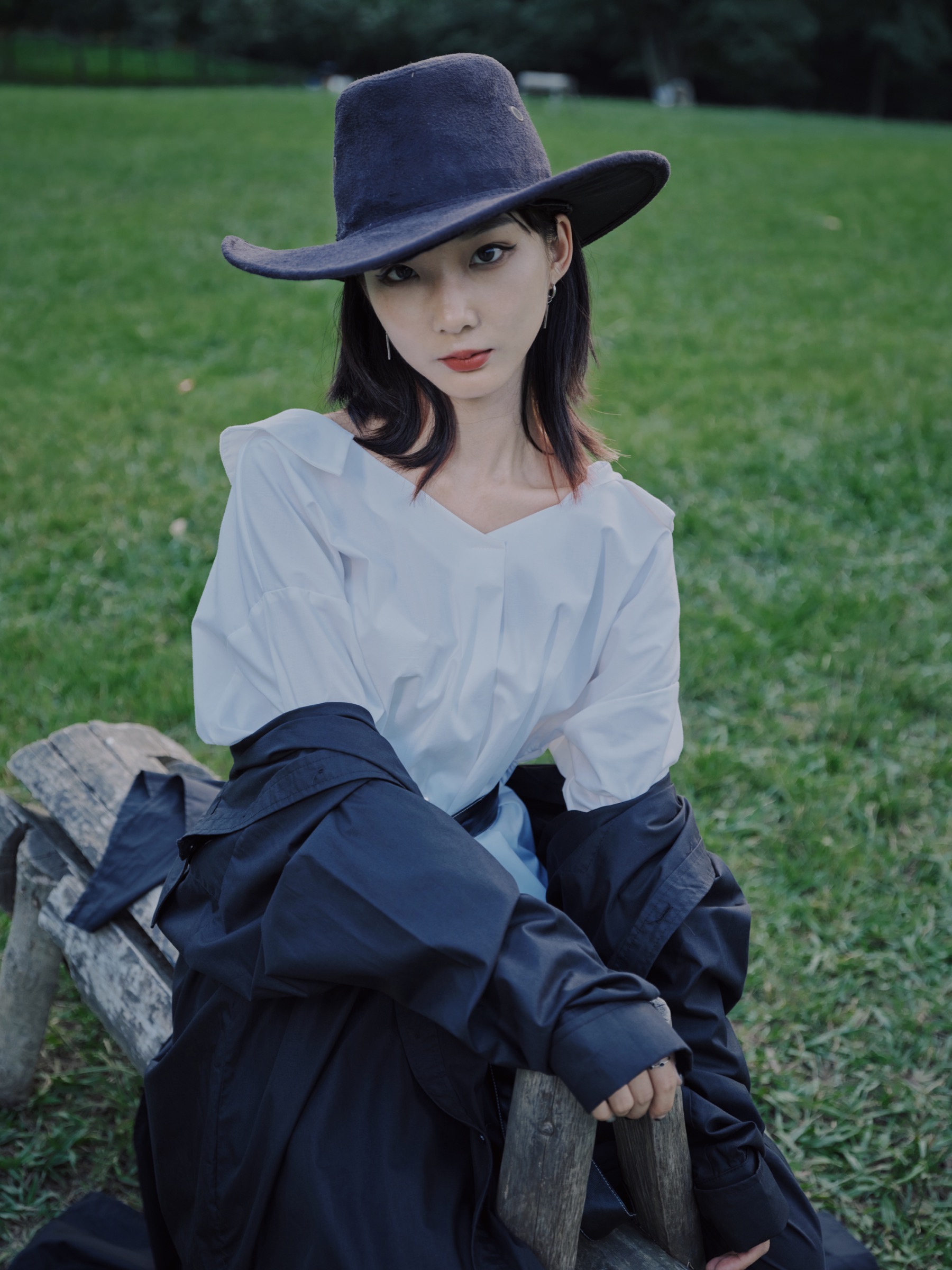戴帽女孩坐在草地长椅上看向镜头。